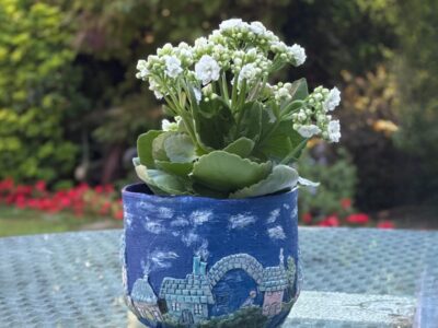 Mystical plant pot featuring colourful homes and winding paths.